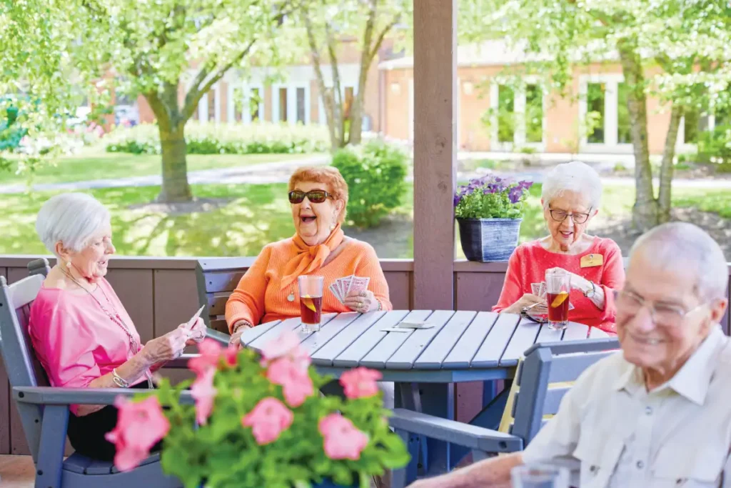 a group of seniors seated on a patio outside playing cards